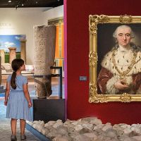 Besucher mit Kindern in der Ausstellung betrachtet einen Waldelefanten und ein Porträt von Carl Theodor